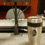 WJCU travel tumbler mug on a desk