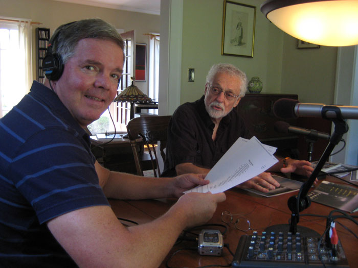 George Bilgere at a table with a microphone with John Donaghue sitting nearby